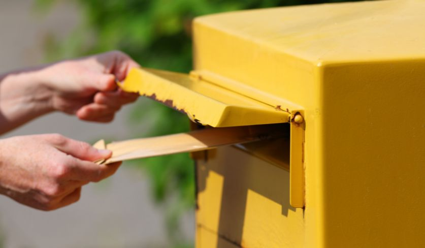 Person die einen Mitteilungsbrief in den Briefkasten steckt