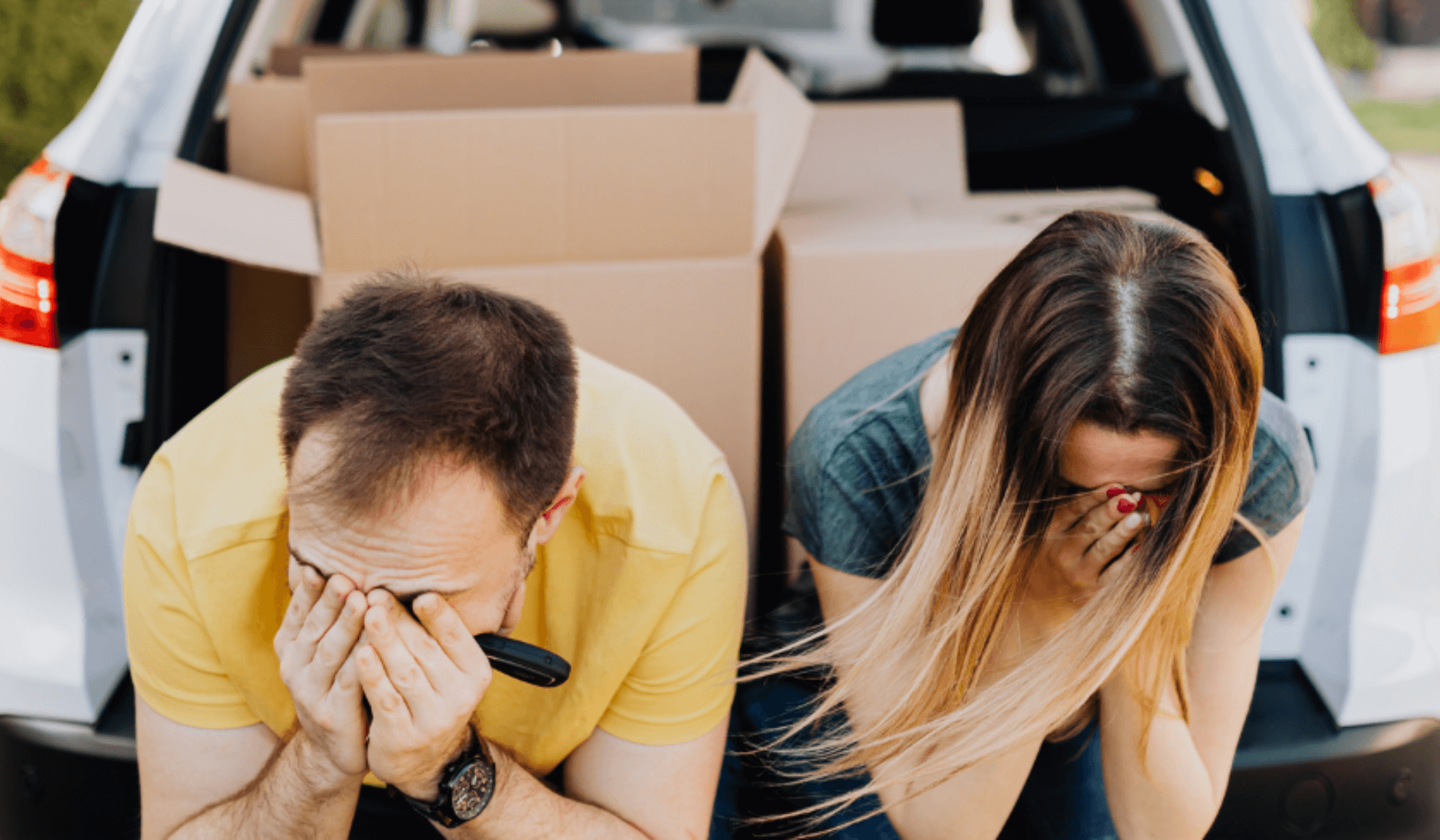 Un couple est assis de manière abattue sur la banquette de leur voiture lors de leur déménagement