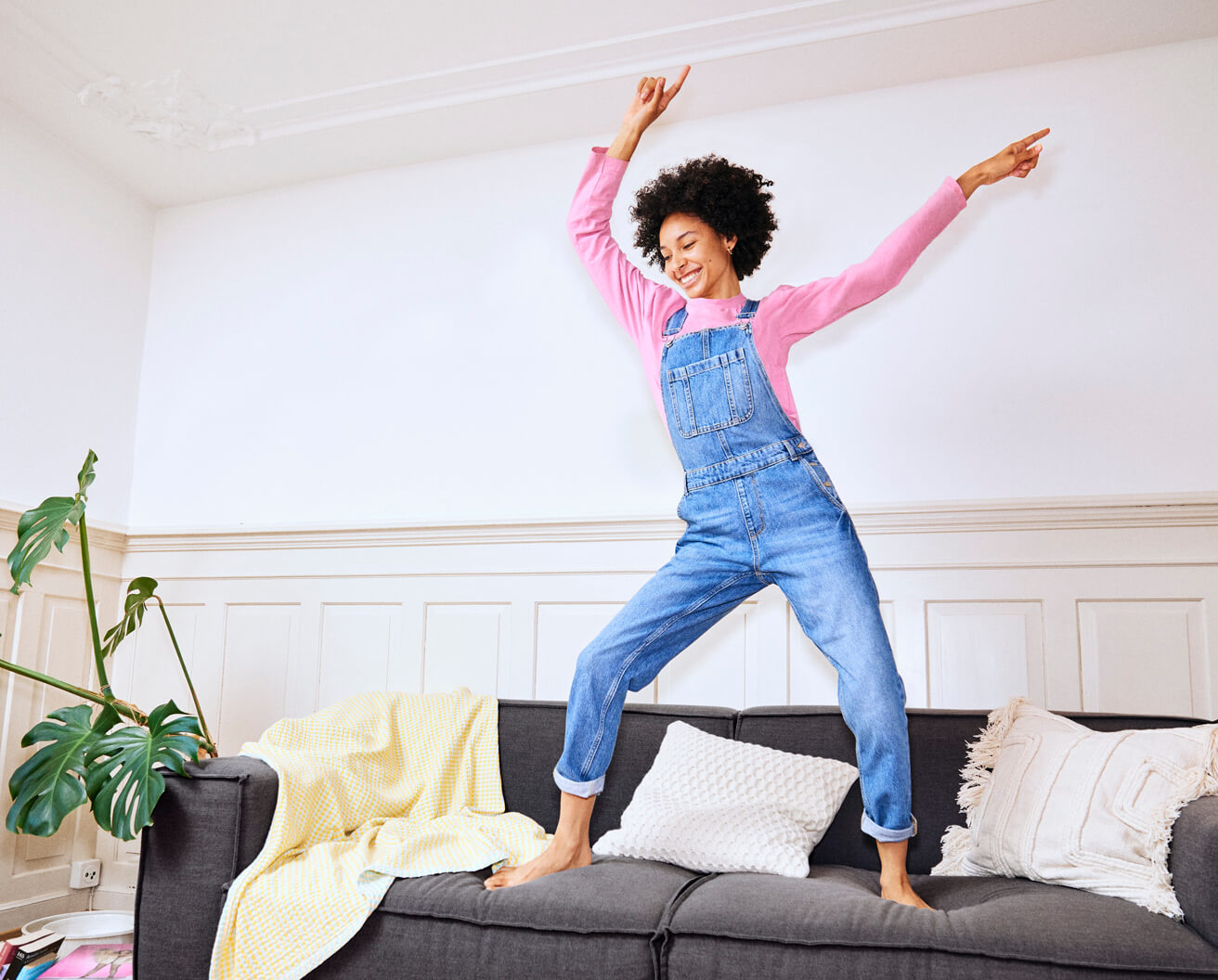 Eine junge Frau tanzt auf ihrem Sofa