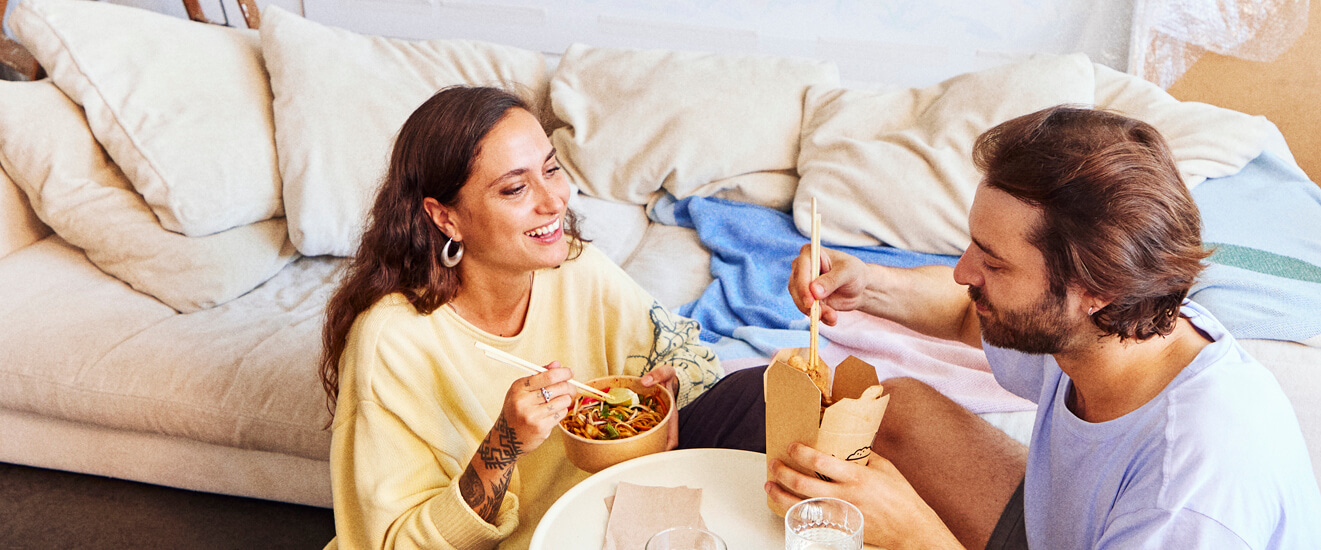 Couple qui mange un repas à l'emporter ensemble dans leur nouvel appartement